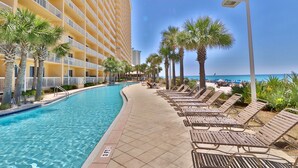 A hotel pool area with a clear view of the ocean, lounge chairs, and palm trees. - 3BR 2BA @ The Calypso Breathtaking View, Walk to Pier Park (Panama City Beach)