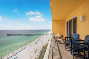 A balcony with a view of a beach and pier, featuring outdoor seating and a door. - 3BR 2BA @ The Calypso Breathtaking View, Walk to Pier Park (Panama City Beach)