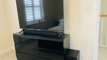 A black entertainment center with a flat-screen TV, built-in drawers, and a shelf.
