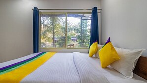 Una camera d'albergo con una grande finestra, un letto con biancheria bianca e due cuscini gialli.