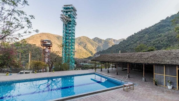 Una piscina con una struttura a tetto di paglia e un'alta torre sullo sfondo.
