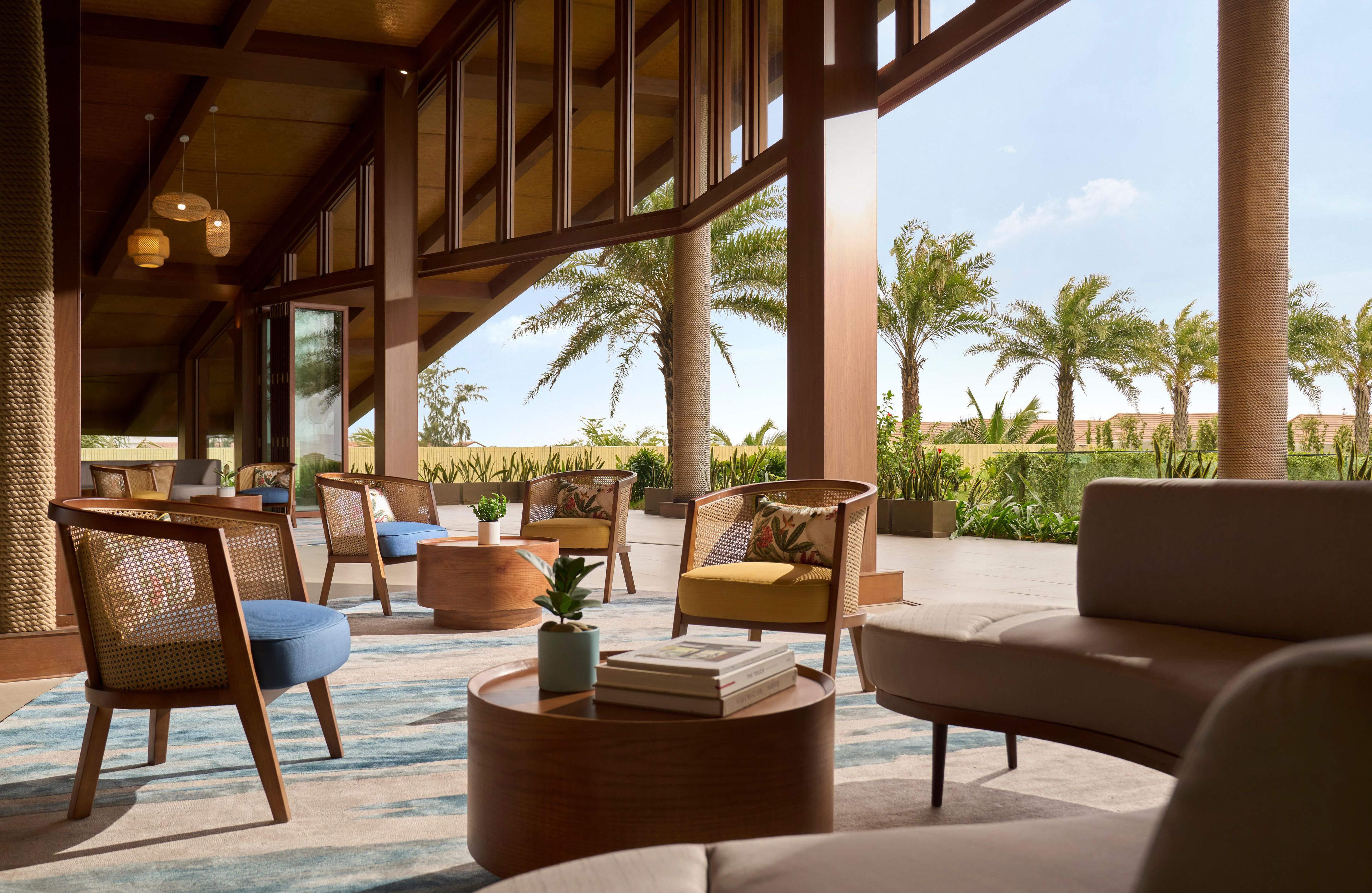 A spacious lounge area with comfortable seating, large windows, and a view of palm trees.