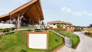 Um hotel moderno com estrutura de madeira marcante, gramado bem cuidado e céu claro.
