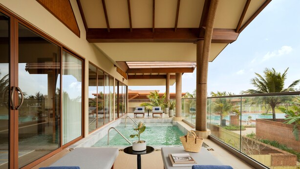 Uma varanda com piscina, cadeiras de descanso e vista para a área da piscina.