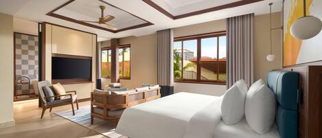 A hotel room with a large bed, a desk, a chair, a TV, and a view of the outside.