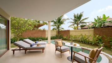 A modern outdoor lounge area with a pool, lounge chairs, and a table.
