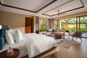 Habitación de hotel con una cama grande, un sofá, una mesita de centro y vistas al exterior.