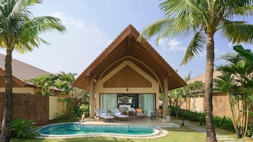 A house with a pool, surrounded by palm trees and a well-maintained lawn.