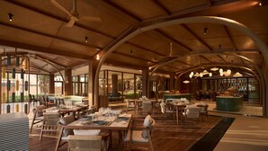 Amplo espaço interior com mesas, cadeiras, mesa de bilhar e bar.
