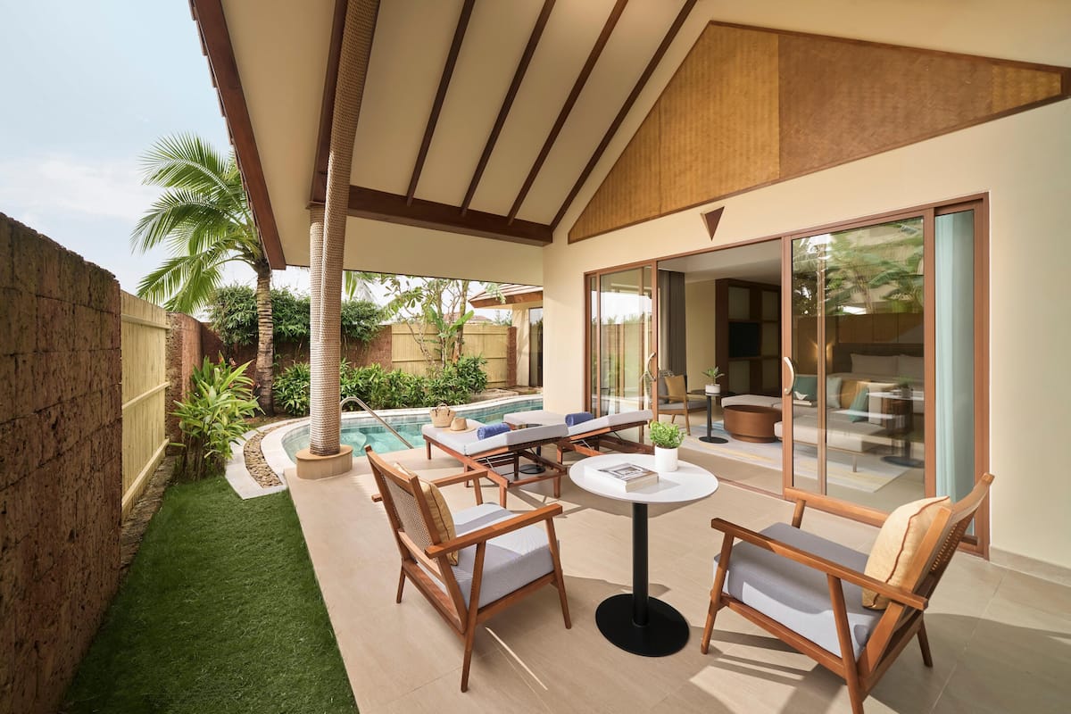 A covered outdoor patio with a pool, wooden furniture, and a view of the interior.