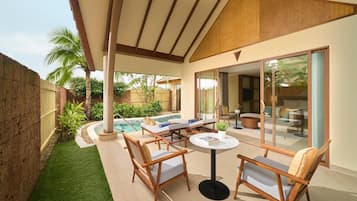 A covered outdoor area with a pool, lounge chairs, and a table.