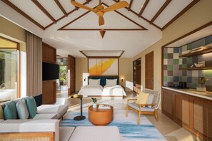 Una habitación de hotel moderna con una cama grande, un sofá, una zona de comedor y un ventilador de techo.