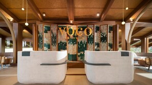 Uma área de recepção com uma parede grande e texturizada e o texto 'VOCO ANING HOTEL'.