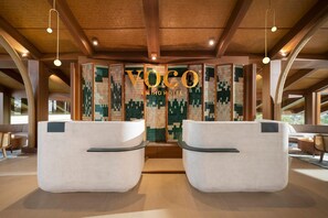 Un área de recepción con una gran pared texturizada y el texto 'VOCO ANING HOTEL'.