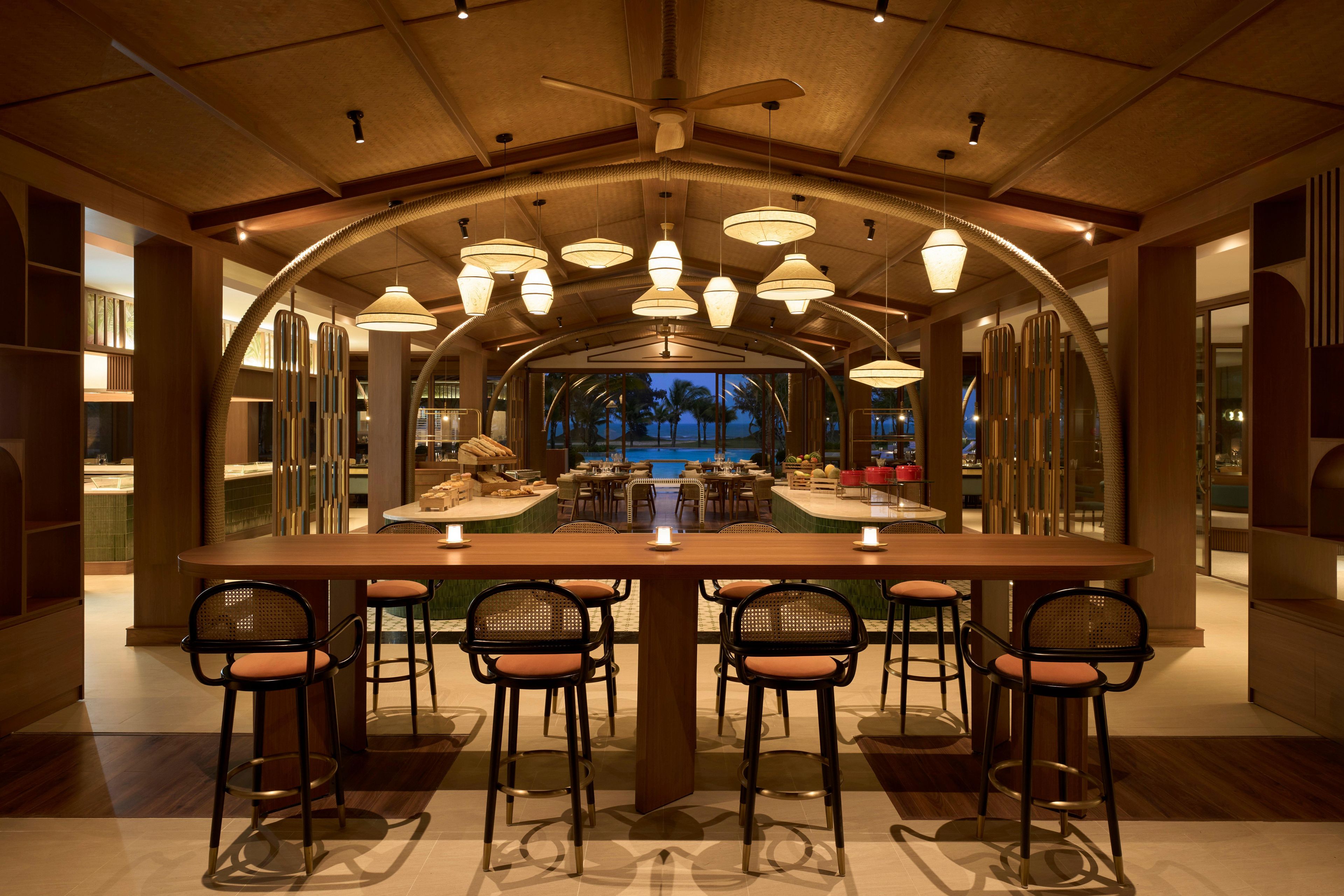 A spacious dining area with a long table, multiple chairs, and a view of the pool.