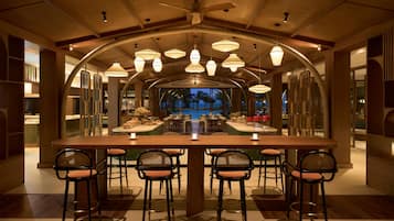 A spacious dining area with a long table, multiple chairs, and a view of the pool.