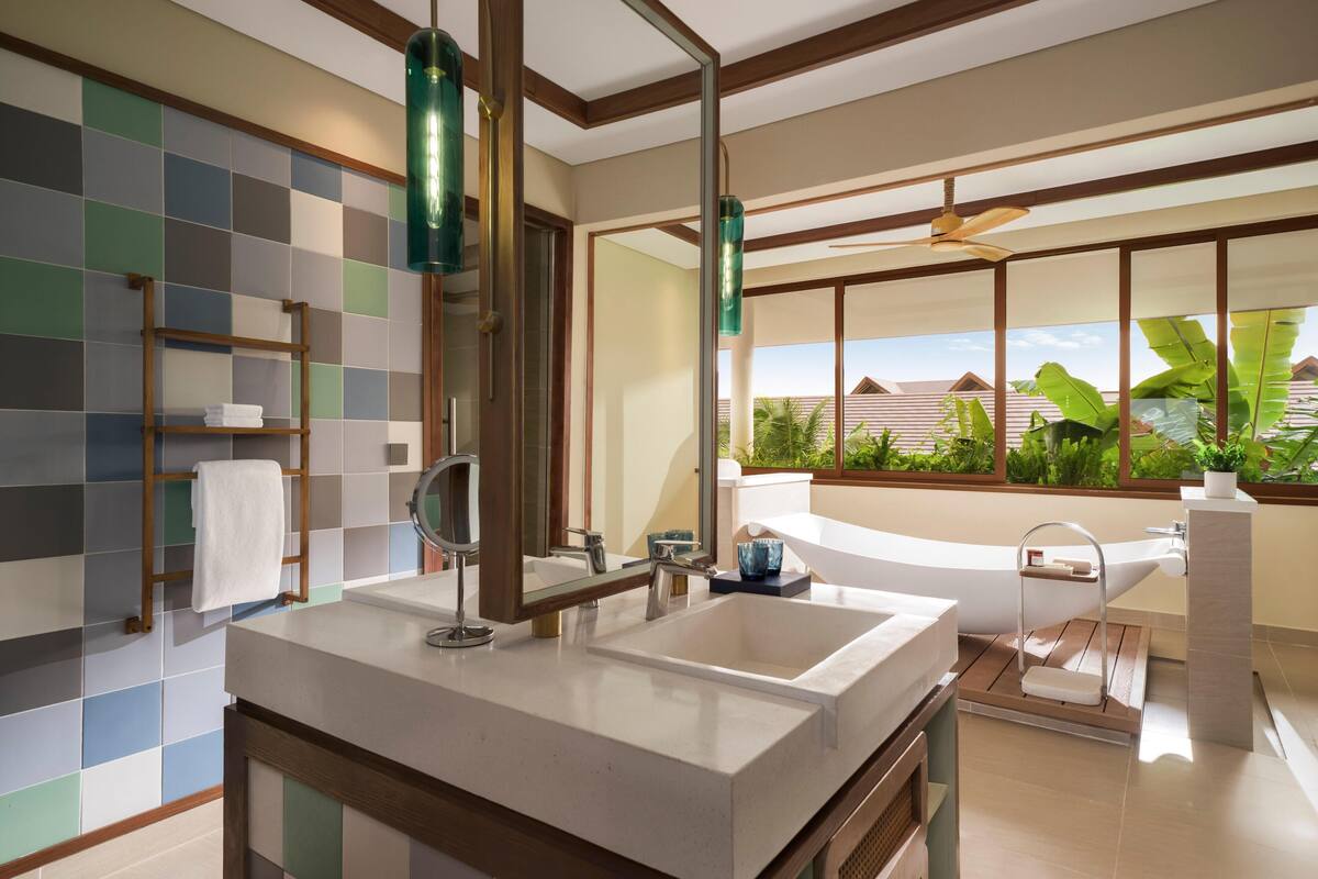 Un baño moderno con una bañera grande, un lavabo doble y un mueble de tocador de madera.