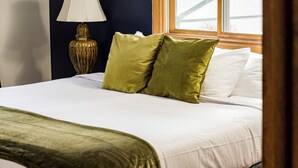 A neatly made bed with white linens and two green pillows, a gold lamp on a wooden nightstand, and a window with a view of a snowy landscape. - Spacious 4-bedroom house, Fenced Yard, Central Denver & Boulder (Denver)