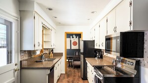 A compact kitchen with white cabinets, a black refrigerator, a microwave, and a stove. - Spacious 4-bedroom house, Fenced Yard, Central Denver & Boulder (Denver)