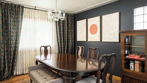 A dining room with a dark wooden table, six chairs, a chandelier, and a cabinet with boxes. - Spacious 4-bedroom house, Fenced Yard, Central Denver & Boulder (Denver)