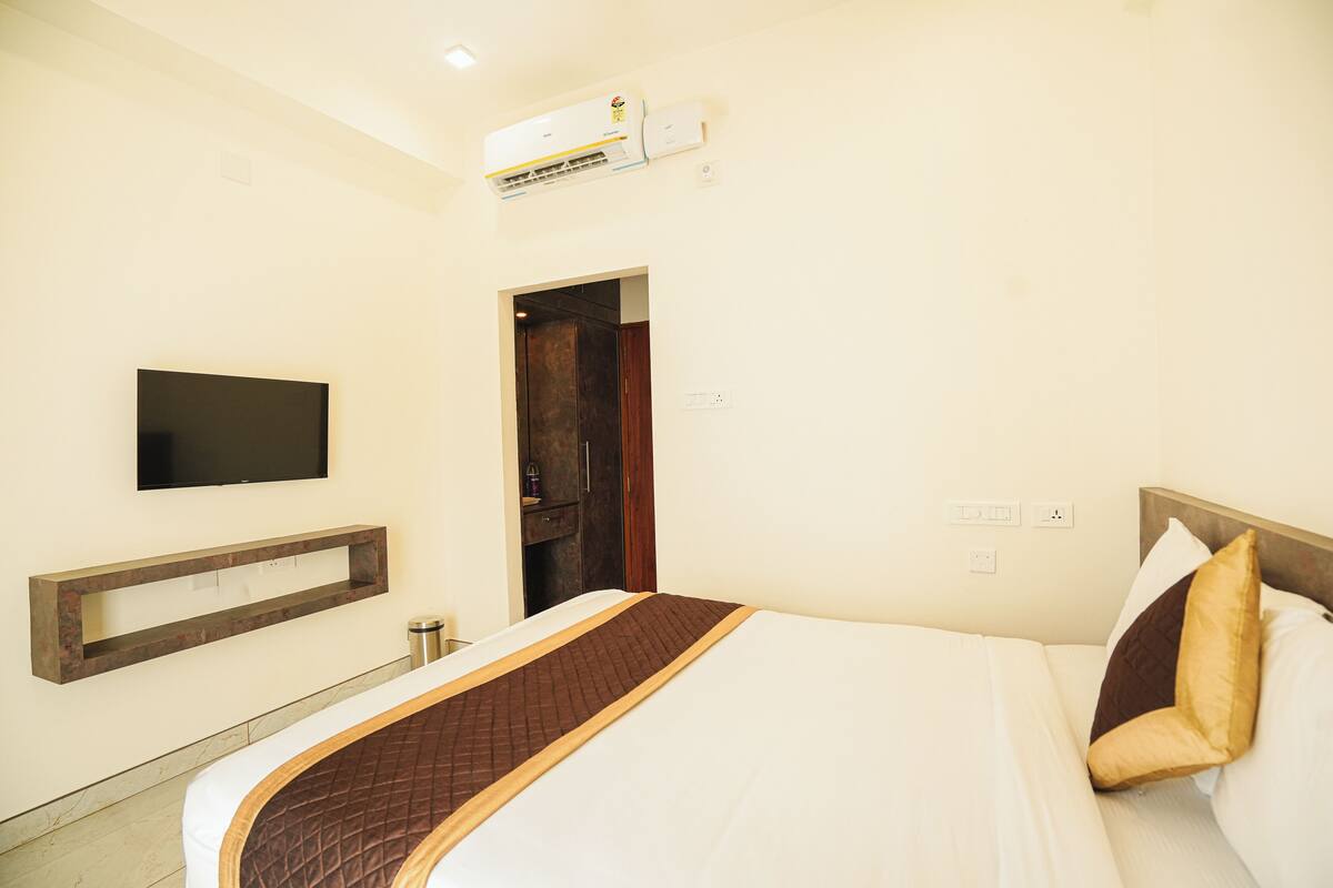 Une chambre d’hôtel équipée d’un lit, d’un téléviseur fixé au mur et d’un appareil de climatisation.