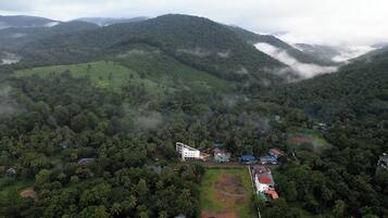 An aerial view of a resort with multiple buildings, surrounded by lush greenery and hills.