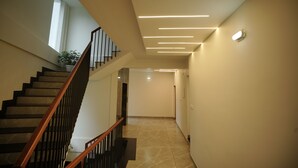 A modern interior with a staircase, a hallway, and recessed lighting. - Sreeja Myst (Chalakudy)