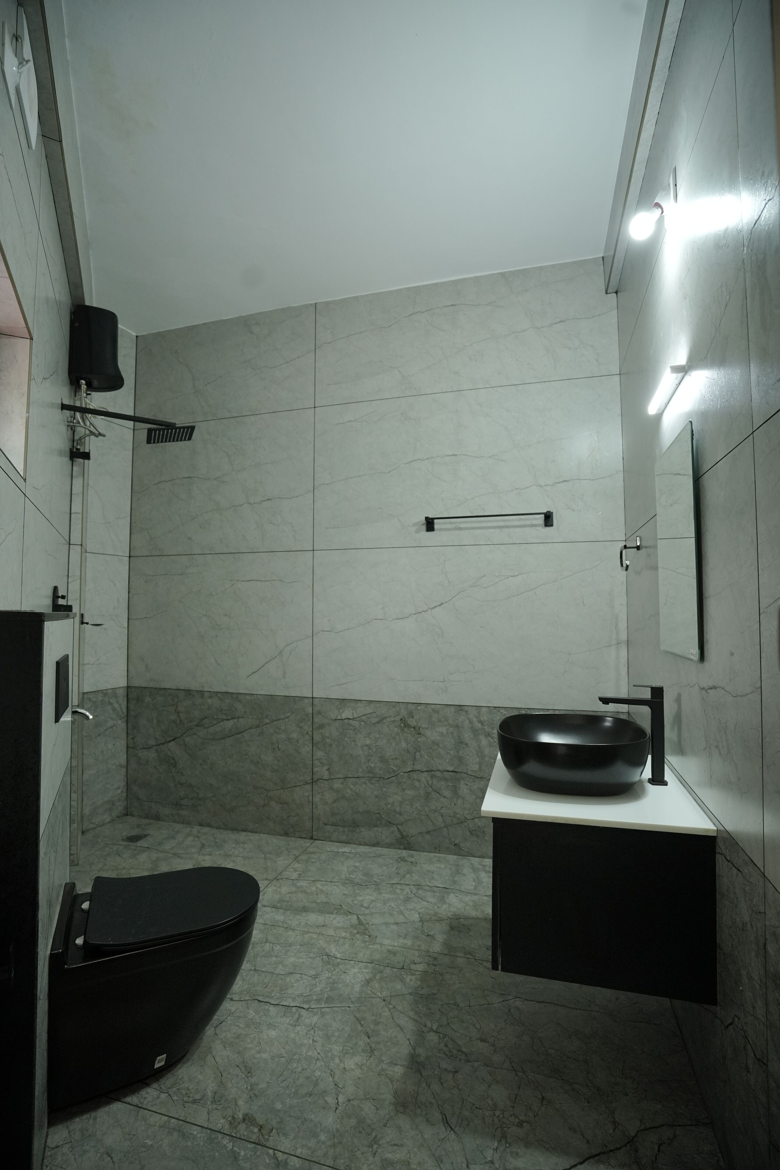 Ein modernes Badezimmer mit Toilette und Waschbecken in Schwarz sowie einem Handtuchhalter.
