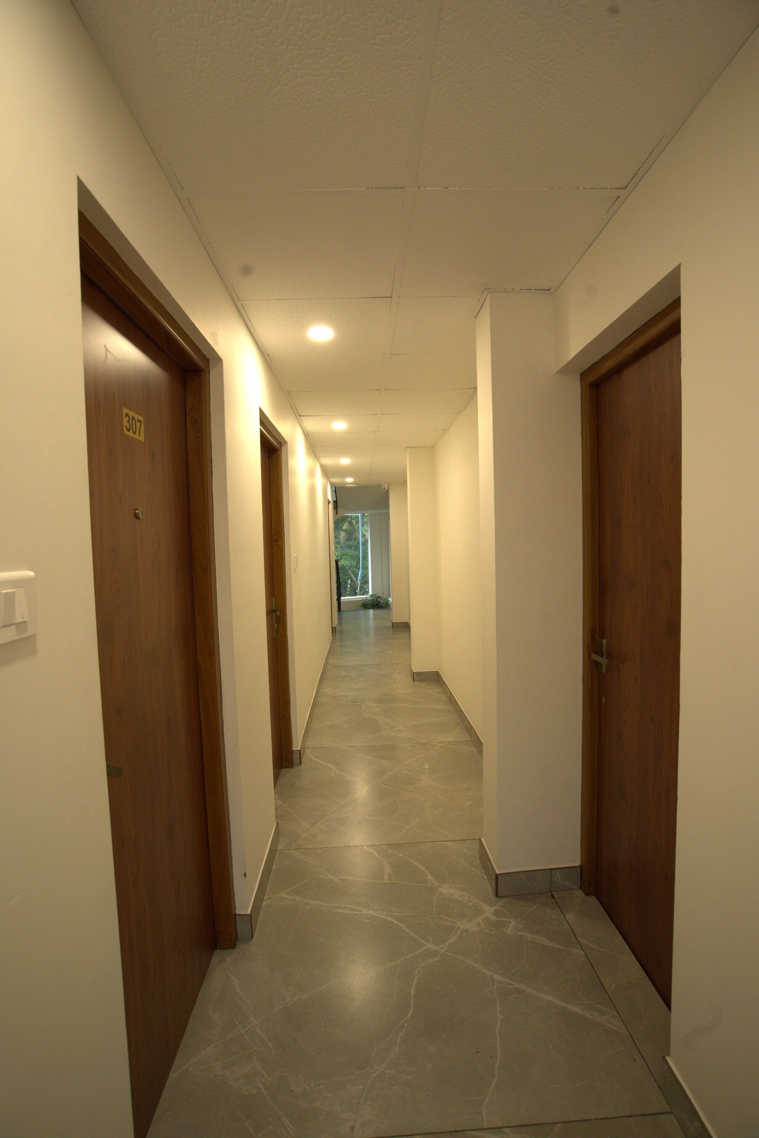 Un couloir avec des portes en bois, numérotées 307, qui donnent accès aux chambres.