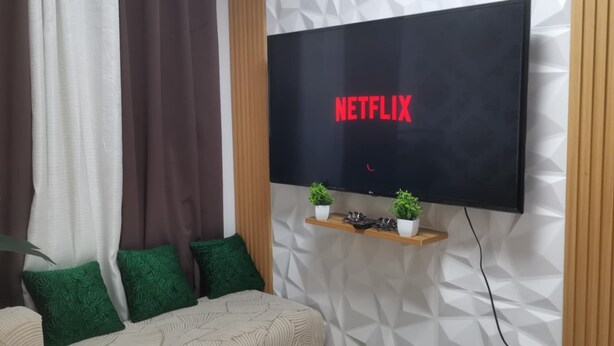 A modern living room with a large flat-screen TV mounted on a textured wall.