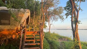 Ein Campingplatz mit einem Zelt und einer Holzleiter, die zu einer Plattform führt.