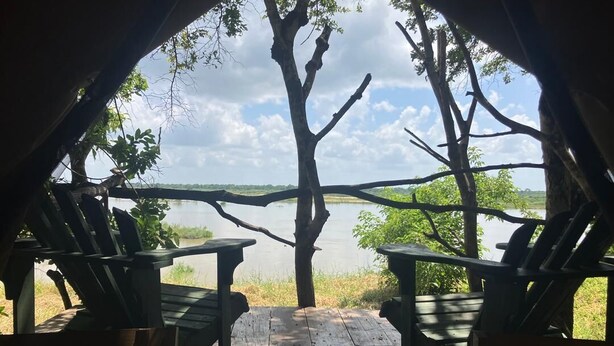 Ein Sitzbereich im Freien mit Holzstühlen und Blick auf einen See.