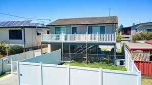 A two-story house with a balcony, a fenced yard, and solar panels on the roof.