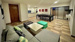 Ein modernes Wohnzimmer mit einer Couch, einem Couchtisch und einem Essbereich mit Tisch und Stühlen.