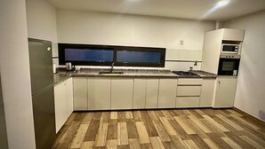 Eine moderne Küche mit weißen Schränken, einer Granitabdeckung, einem eingebauten Backofen und einer Mikrowelle.