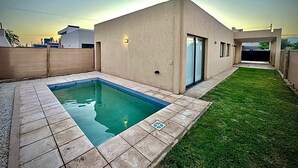 Ein modernes Haus mit Schwimmbad, kleinem Rasen und Garage.