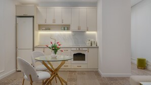 A compact kitchen with white cabinets, a glass table, and a small dining area. - Sweet Home Prime Apart-Hotel (Yerevan)