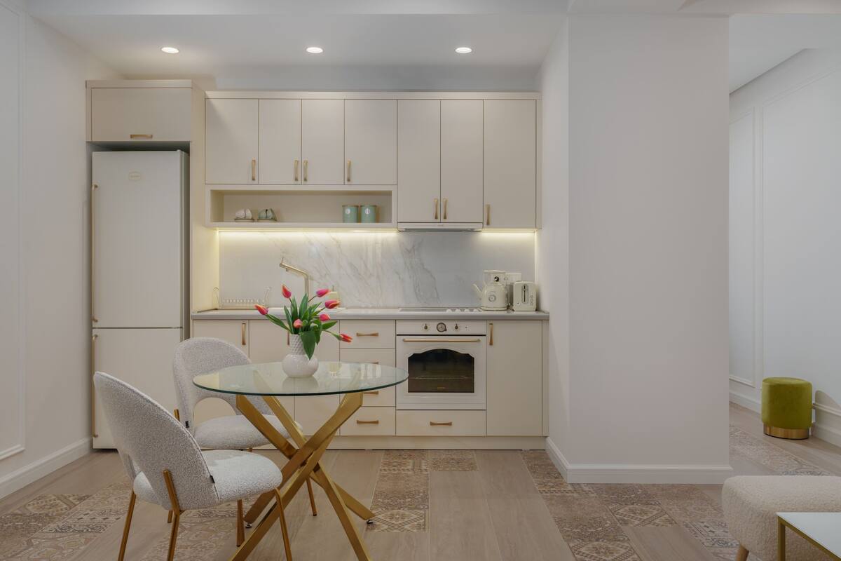 A compact kitchen with white cabinets, a glass table, and a small dining area.