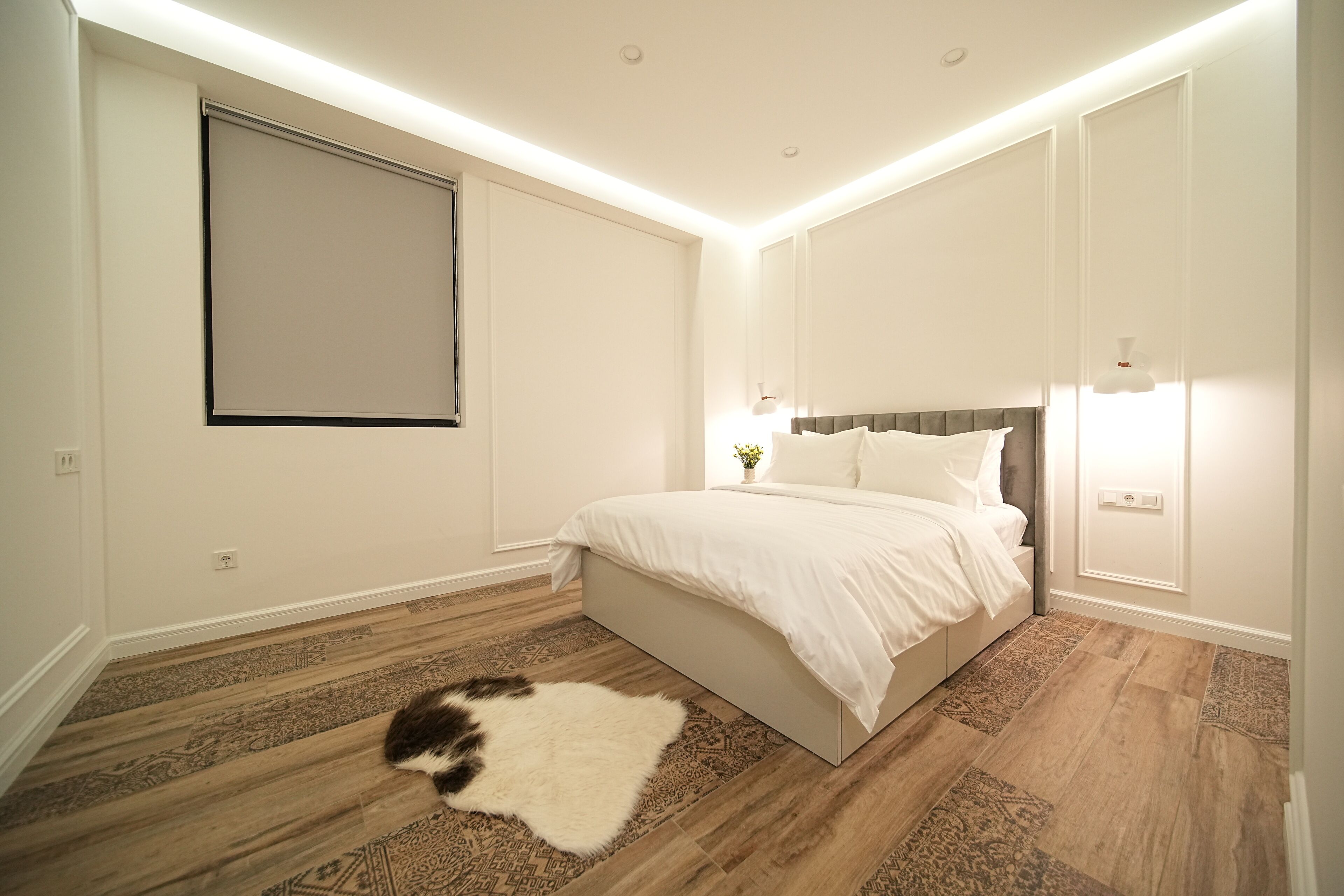 Een slaapkamer met een bed, een groot raam en een houten vloer.