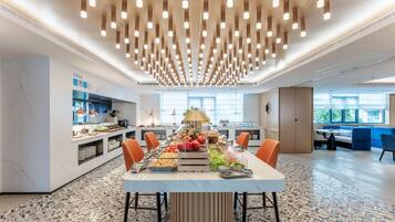 Una cocina moderna con una isla central, equipada con diversos electrodomésticos y una exposición de frutas.