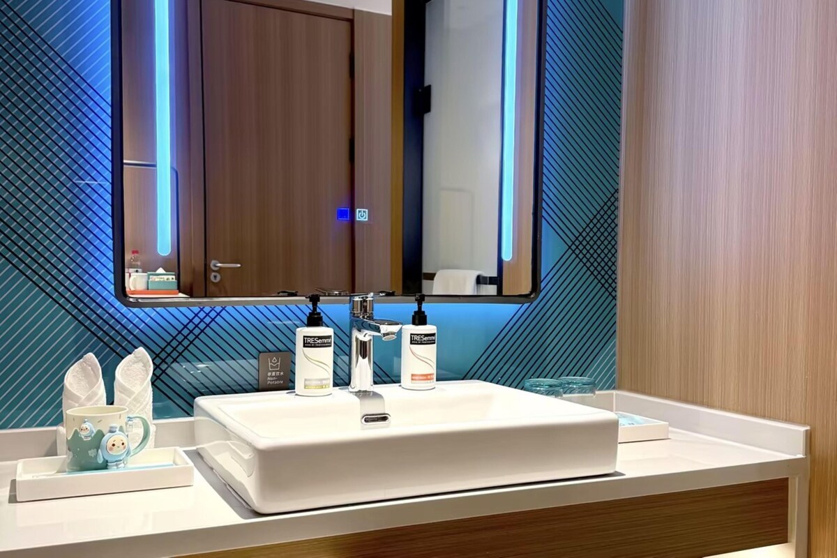 A modern bathroom with a large mirror, two sinks, and a vanity.