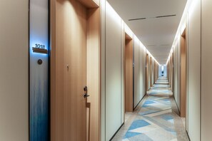 A hotel corridor with wooden doors, numbered 1018, and a patterned carpet. - Holiday Inn Express Haikou World Trade Center (Haikou)