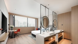 A modern hotel room with a large bed, a desk with a chair, a vanity with two sinks, and a large window offering a city view. - Holiday Inn Express Haikou World Trade Center (Haikou)