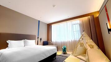 A hotel room with a large bed, a small seating area, a tent-like structure, and a large window with curtains.