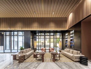 A modern lobby with a sectional sofa, round coffee tables, and a patterned floor. - Holiday Inn Express Haikou World Trade Center (Haikou)