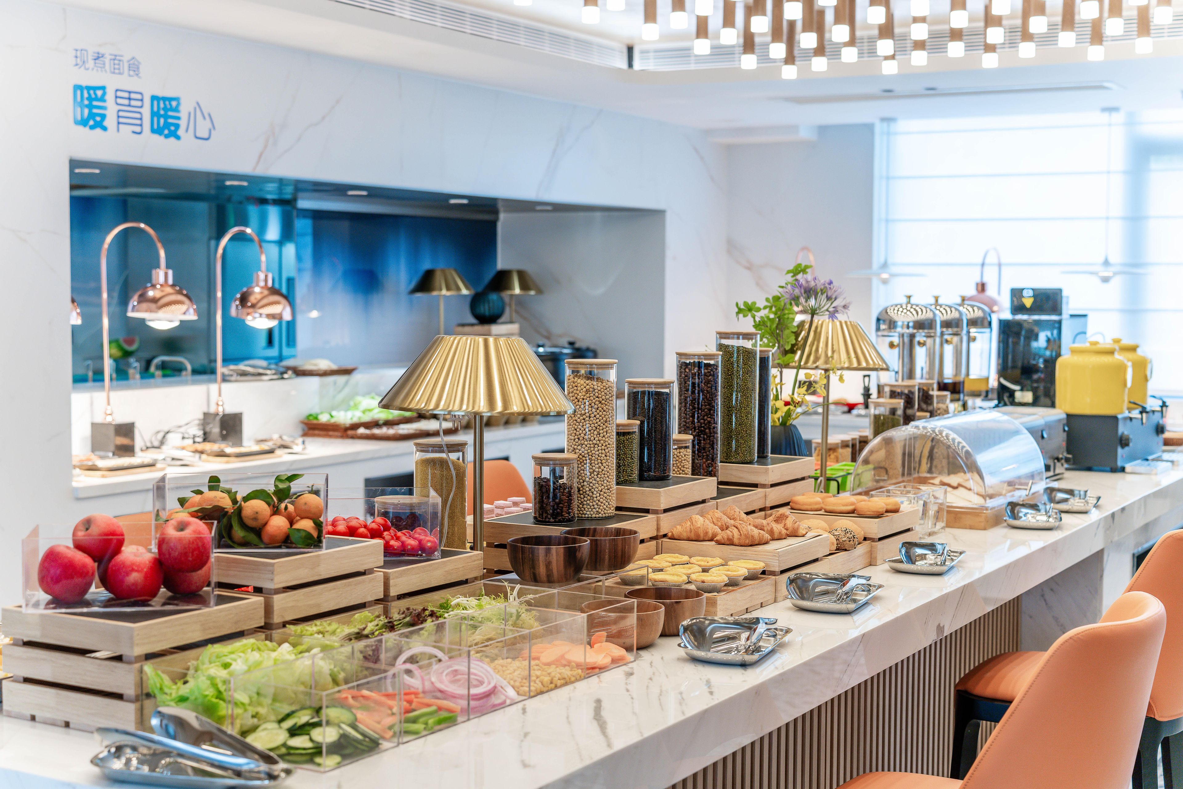 Montaje tipo buffet con diferentes alimentos y una cocina moderna al fondo.