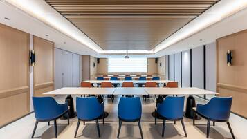 A conference room with a long table and blue chairs, wooden paneling on the walls, and a ceiling with a wooden slat design.