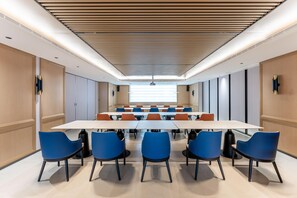 A conference room with a long table and blue chairs, wooden paneling on the walls, and a ceiling with a wooden slat design. - Holiday Inn Express Haikou World Trade Center (Haikou)
