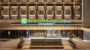 A hotel entrance with a modern facade, multiple balconies, and a sign indicating a Holiday Inn Express. - Holiday Inn Express Haikou World Trade Center (Haikou)