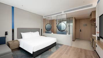 Een moderne hotelkamer met een groot bed, een nachtkastje, een garderobe, een spiegel en een televisie.